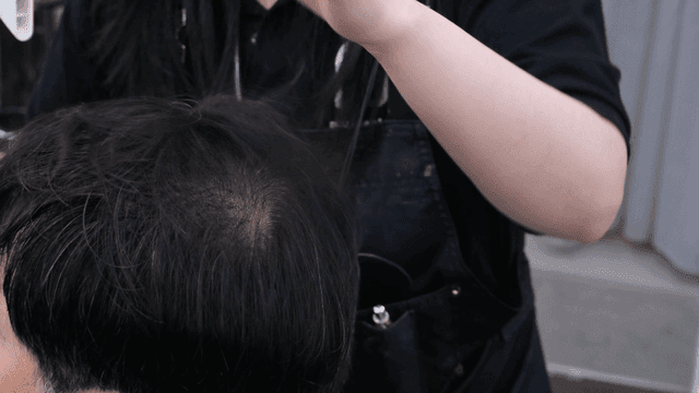 Hairdresser drying customer's hair with hairdryer