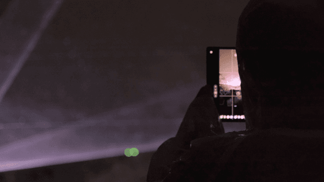 Person filming night event with smartphone