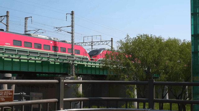 Red train crossing green bridge