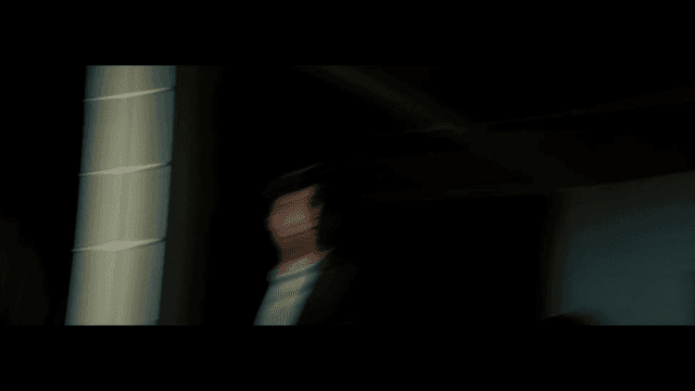 테이프로 입이 막힌 여성 옆에서 쌍절곤을 들고 있는 정장을 입은 남자