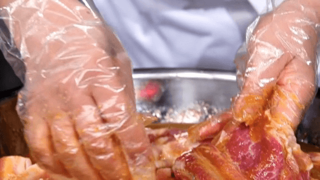 Hands marinating raw galbi in a bowl