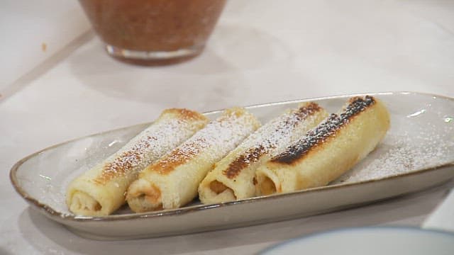 Powdered sugar sprinkled on rolled pancakes on dish