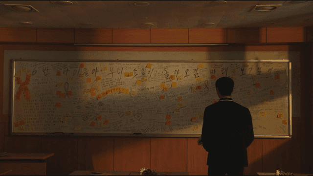 Male student's back view as he looks at chalkboard filled with memorial messages.