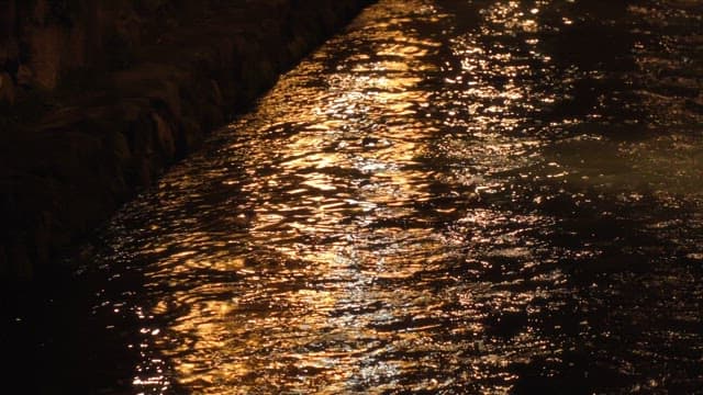 Streetlights reflected in the water flowing along a quiet canal