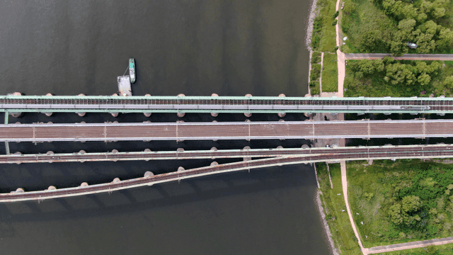 View looking down at railway bridge over river where high-speed train passes.