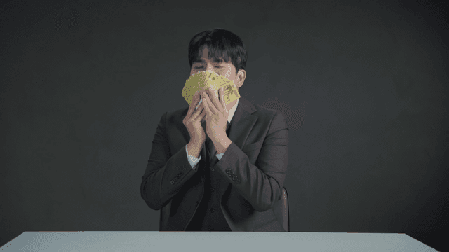 만족스러운 표정으로 돈 냄새를 맡는 남자