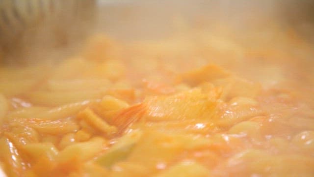 Stirring boiling spicy tteokbokki with a ladle