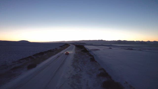 Car driving on a snowy road at dawn