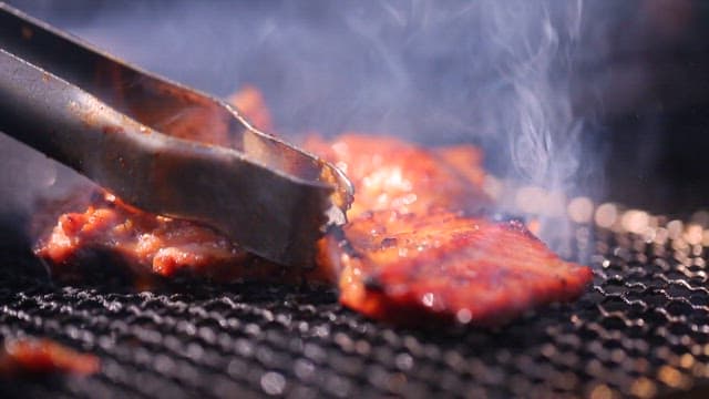 Grilling marinated pork ribs on a grill over burning charcoal