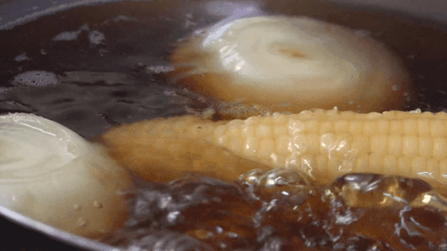 Corn and onions boiling in a pot