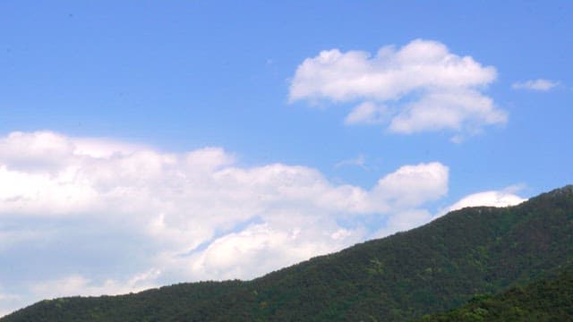 Scenic mountain with a clear blue sky and fluffy clouds