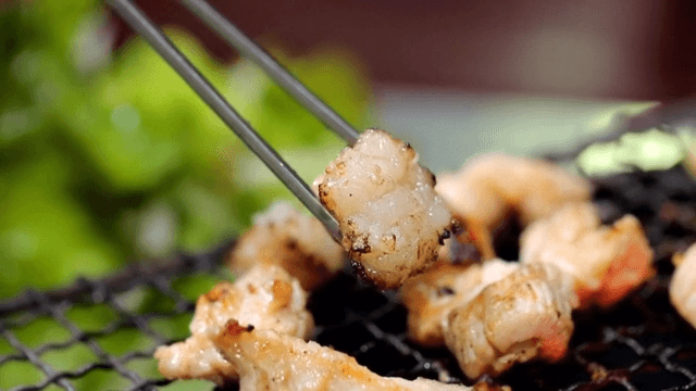 Grilled beef large intestines picked up with chopsticks