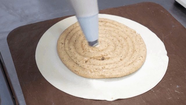 Baker piping almond cream into pastry dough