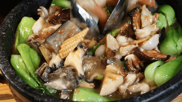 Jeon Ga Bok mixed on hot stone plate containing seafood and vegetables