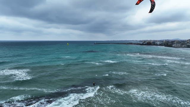 Kitesurfing on a windy beach with waves