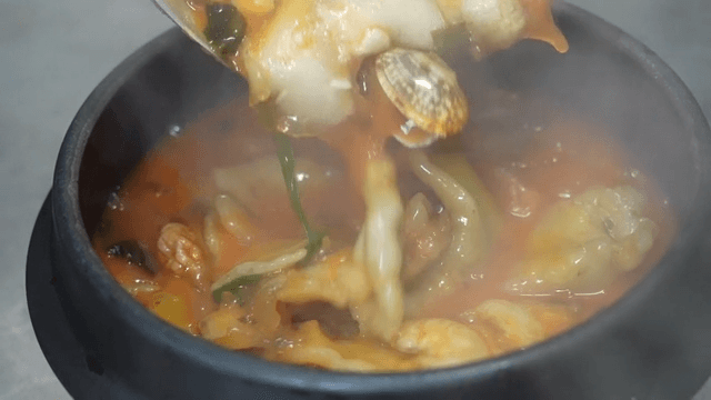 Steaming hot earthenware pot filled with spicy dumplings