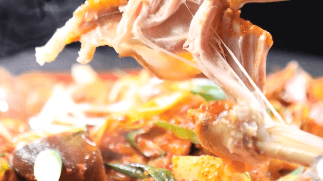 Steaming hot spicy chicken stew, tongs for tearing chicken legs