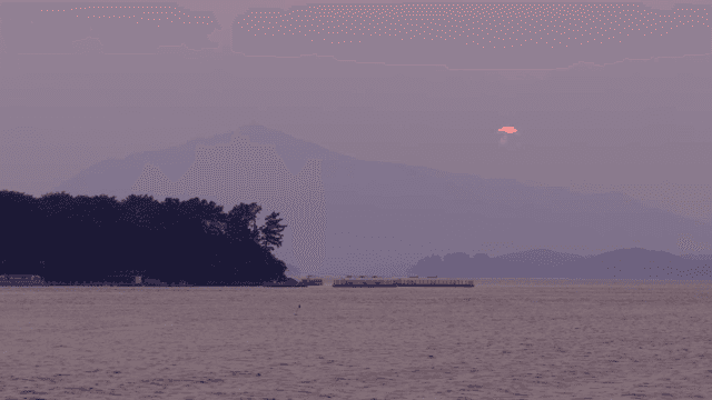 Sunset over a calm sea with distant mountains
