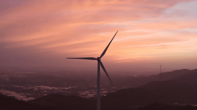 Wind turbines in a mountainous area under a pink-tinted sky