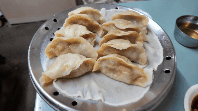 Steamed kimchi dumplings on a table with side dishes