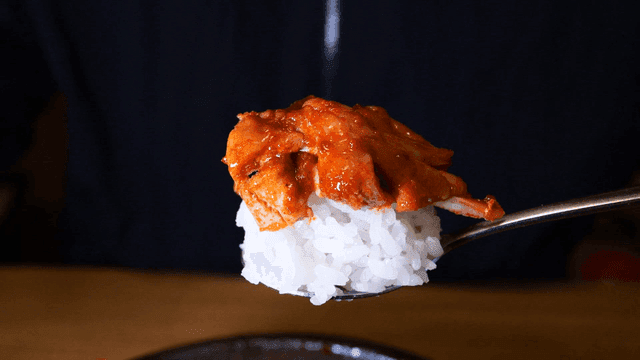 젓가락으로 집은 매운 닭고기와 밥