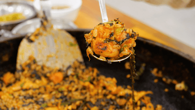 Spoon scooping out Dakgalbi fried rice with vegetables and meat