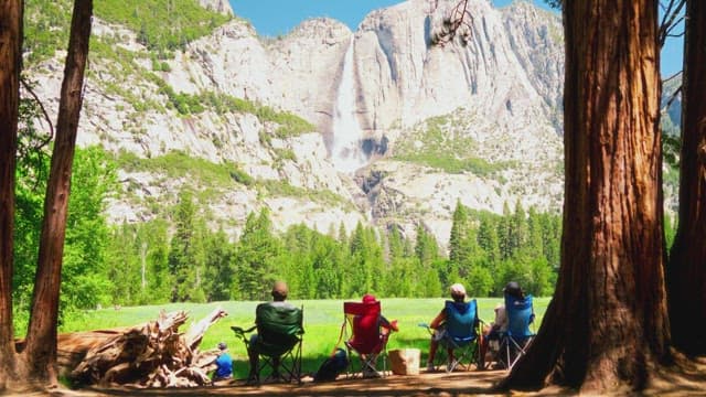 People Enjoying Scenic Waterfall from Forest Campsite