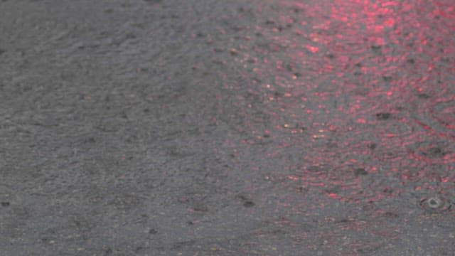 Raindrops creating ripples on a pavement