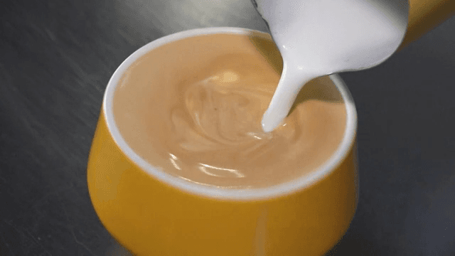Milk being poured into a cup of coffee