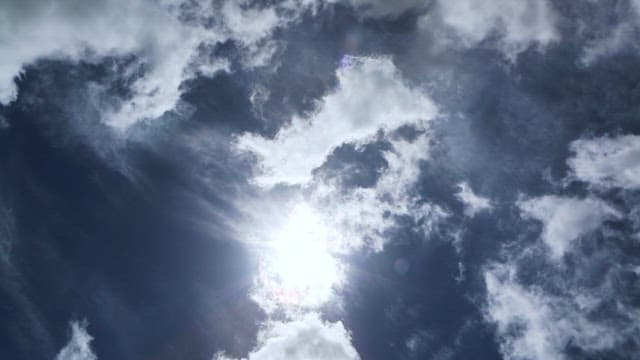 한낮에 흘러가는 구름과 태양이 보이는 하늘