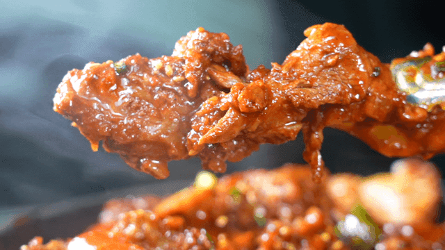 Spicy braised ribs lifted with tongs