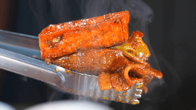 Spicy stir-fried pork picked up with tongs