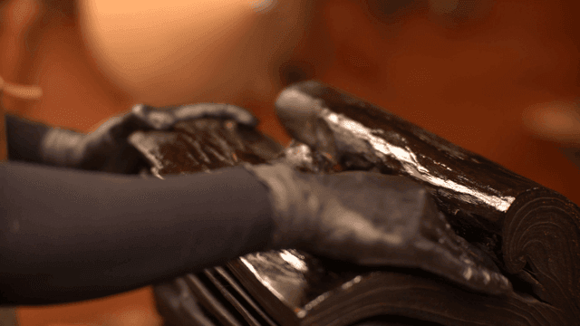 광이 나는 나무 조각품에 마감 오일을 바르는 장인