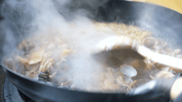 Spicy stir-fried seafood noodles cooking in a wok