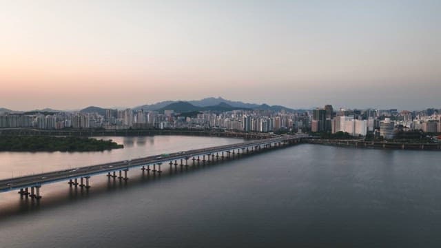 Sunset over tranquil river with a bridge and cityscape