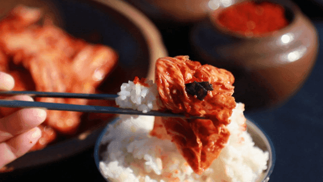 Kimchi and white rice picked up with chopsticks