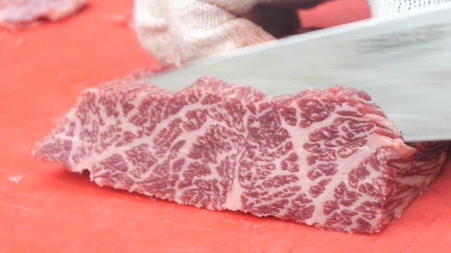 주방에서 붉은 도마 위에 마블링이 있는 소고기 썰기