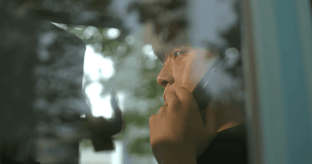 Man making call on payphone visible through window