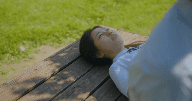 나무 벤치에서 누워서 휴식 중인 소녀