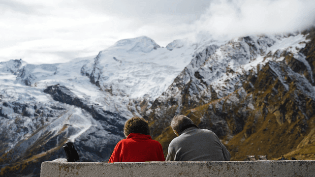 Elderly couple admiring snow-covered mountains