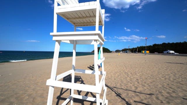 Beach with volleyball net and surfboard under clear sky