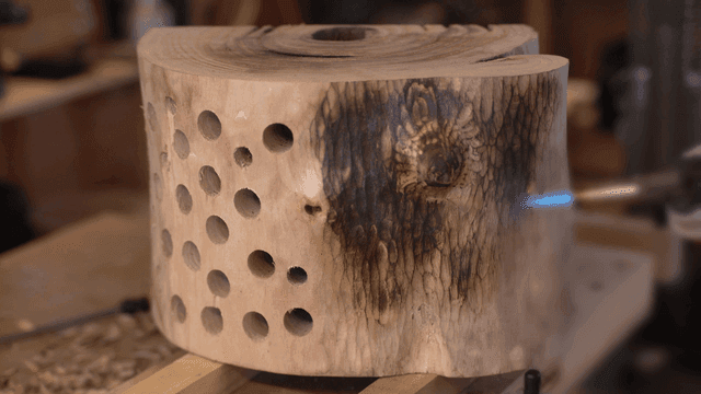 나무 조각품의 표면을 토치로 그을리는 장인