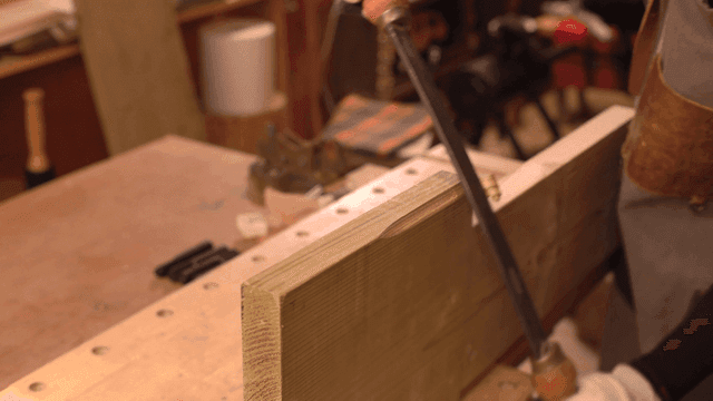 목수가 손 도구로 나무를 다듬는 모습