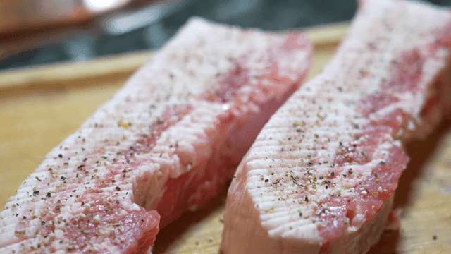 Seasoned pork belly on wooden cutting board