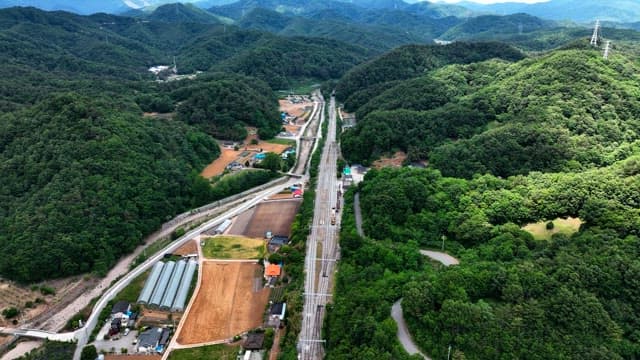 밝은 날 울창한 녹색 산악 풍경을 가로지르는 철도