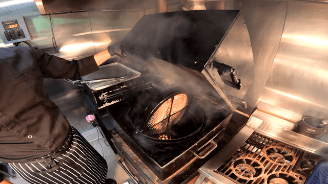 Chef grilling barbecue meat on rotating grill in kitchen