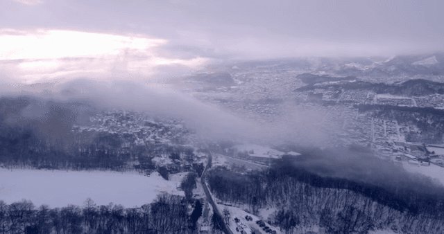 Snowy landscape with fog over the village
