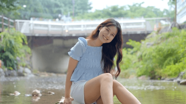 A woman sitting by a stream smiling
