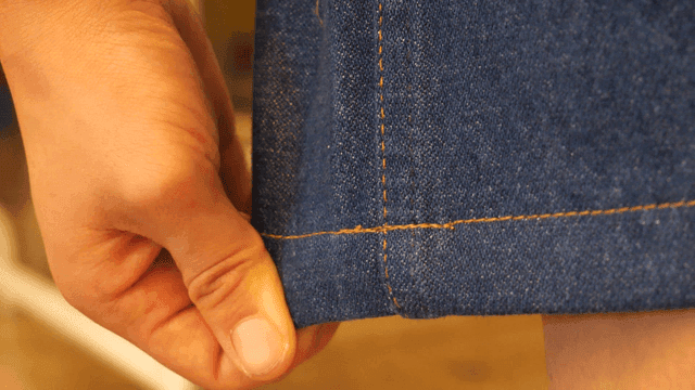 Hand holding end of denim fabric