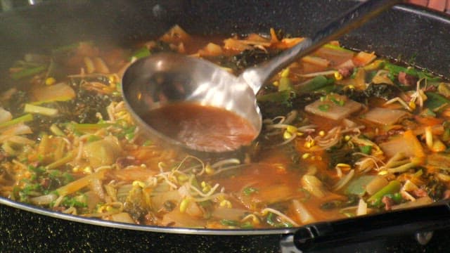 Ladling the hot and spicy Korean beef soup into a bowl